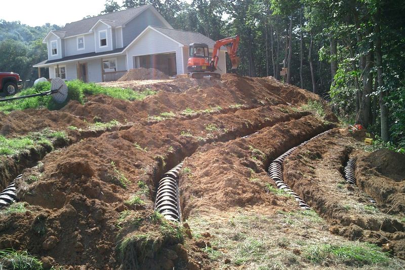 Terraced drain-field lines cut into a hillside below a house